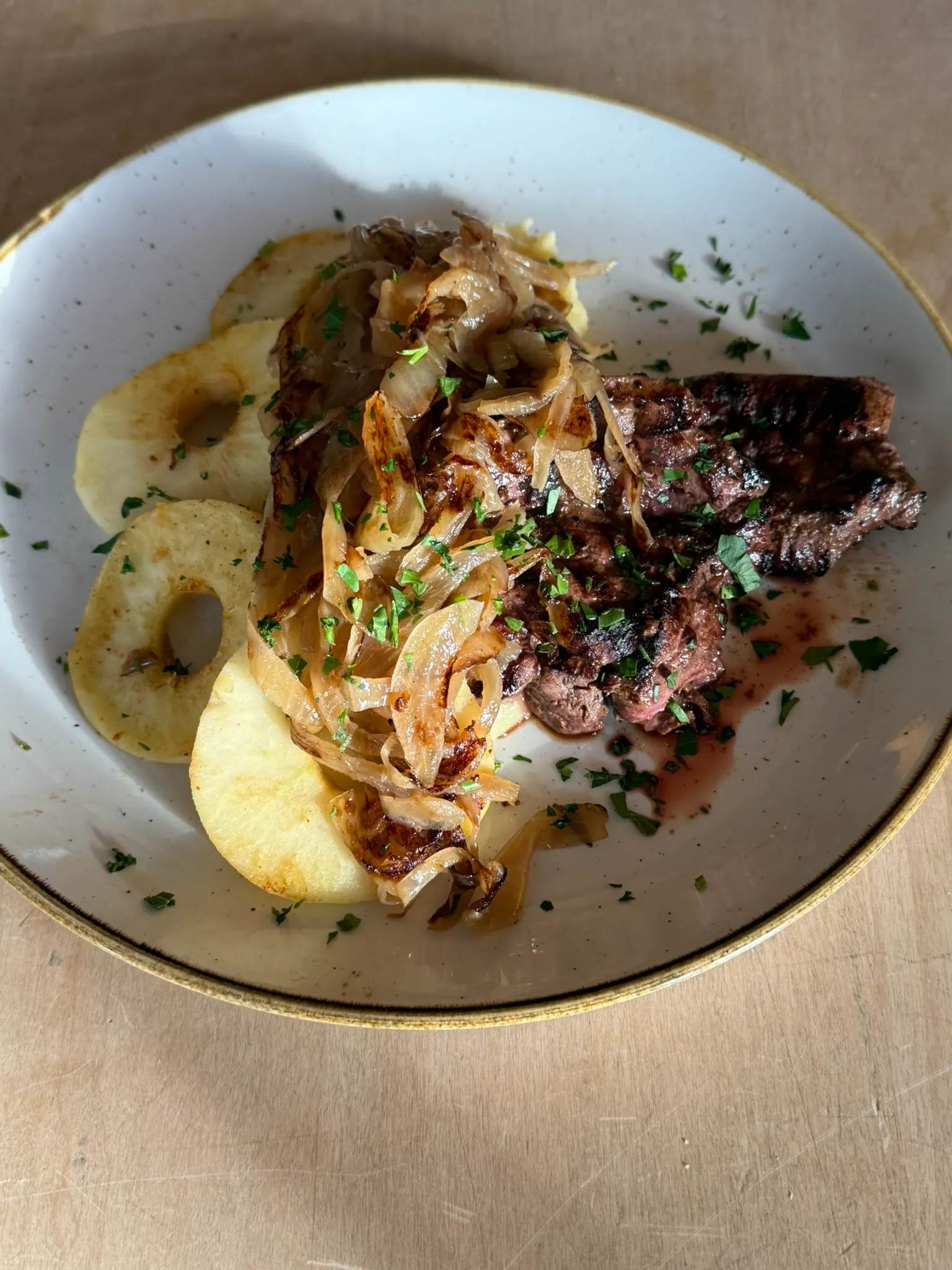Gegrilltes Fleischgericht mit gebratenen Zwiebeln und Apfelspalten