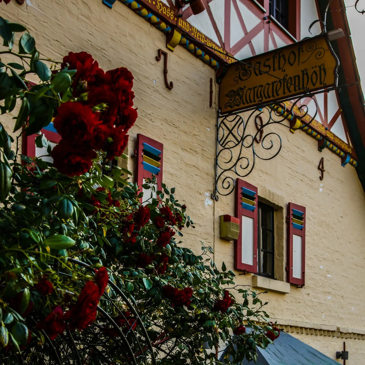 Historischer Schriftzug und dunkelrote Rosen an der Fassade des Gasthofs Margaretenhöh
